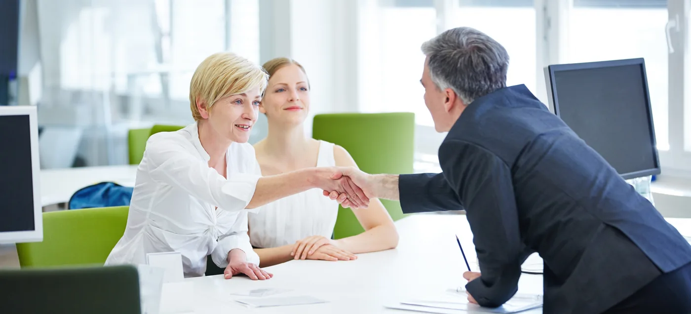 Handschlag am Besprechungstisch zum Auftakt einer Zusammenarbeit